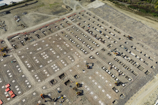 Aerial view of a battery energy storage system construction site with concrete foundations, excavation pits, and heavy machinery on a large earthwork plot in the United Kingdom.