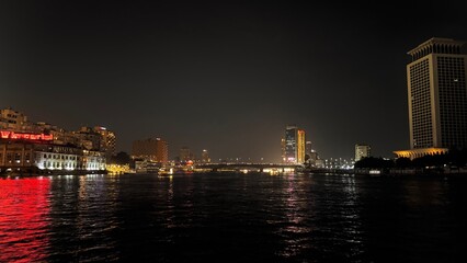 Fototapeta premium Night view of the Nile river reflecting city lights and illuminated skyscrapers of downtown Cairo