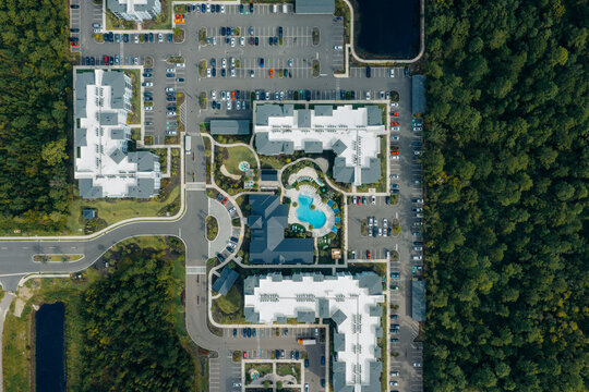 Aerial view of a residential apartment complex with a central swimming pool, parking lots, and surrounding dense forest in Jacksonville, Florida, United States.