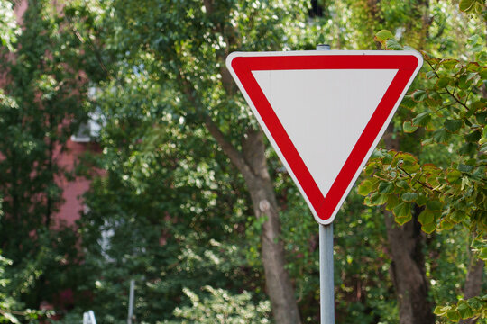 Yield sign in a green area beside a building