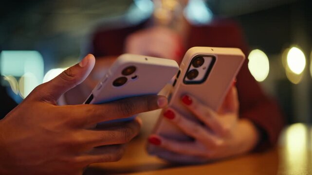 Closeup smartphone multiethnic hands bar table. Colleagues browsing phone night.