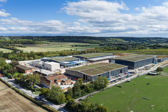 Aerial view of a large data center complex with green roofs under construction, surrounded by rural fields and rolling hills in the United Kingdom.