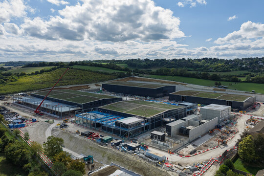 Aerial view of a large data center construction site featuring multiple modern buildings with green roofs, surrounded by rural landscape in the United Kingdom.