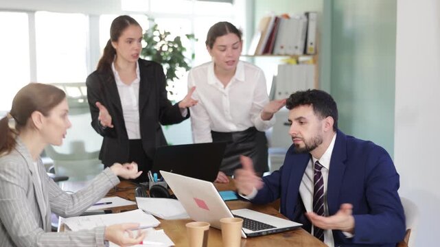 Aggressive office team yelling and gesturing at upset guy after project failure in office 