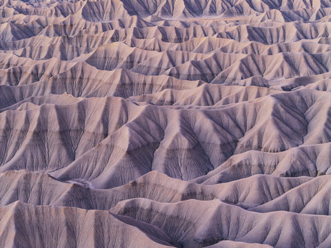 Aerial view of the intricate, eroded badlands of Factory Butte, featuring sharp ridges, deep gullies, and soft desert light in Wayne County, Utah, United States.