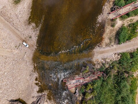 Aerial view of a damaged bridge crossing a river with gravel roads and a white vehicle nearby in Bonnievale, Western Cape, South Africa.