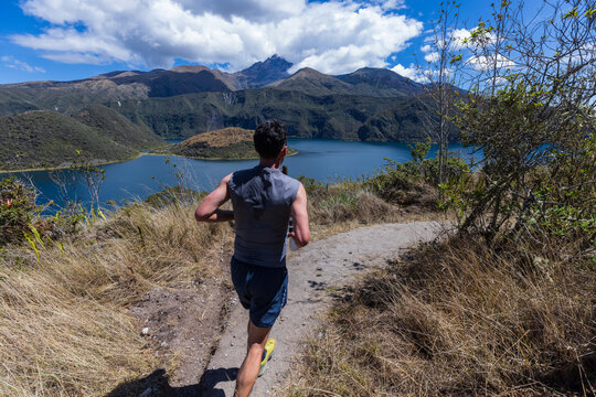 Athletes participating in a outdoor trail running competition around the scenic Cuicocha volcanic lake crater on a bright sunny day