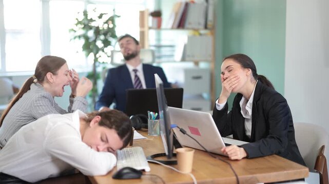 Tired team sits at a desk in a modern office, working overtime on a project and relaxing at the workplace. Tired employees of the company relax in the office . High quality 4k footage