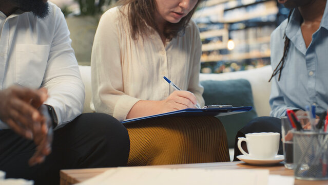 Close up of businesswoman reading paperwork before signing on a rooftop terrace, reviewing terms and conditions before completing a deal and shaking hands with businesspeople during a meeting.