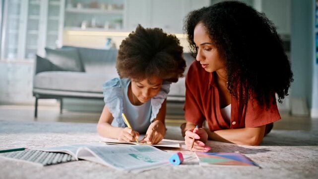 Mom helping daughter homework floor living room. Mixed race family learning.