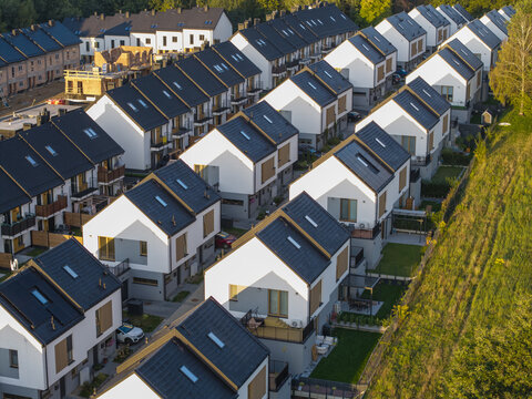 Aerial view of a modern residential housing development featuring rows of white houses with dark roofs and small gardens in Wieliczka, Lesser Poland Voivode, Poland.