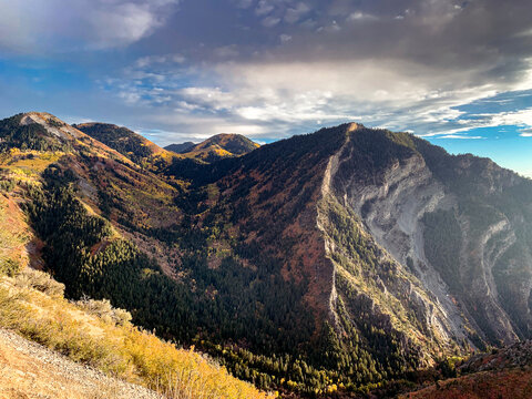 Aerial view of Kyhv Mountain with autumn foliage, evergreen forests, and rocky slopes overlooking the Utah Valley in Utah County, Utah, United States.