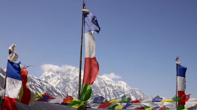 Colorful Buddhist prayer flags flutter gently above a sacred stupa in Nepal, creating a serene spiritual atmosphere in the Himalayan landscape. Traditional Tibetan flags display vibrant colors