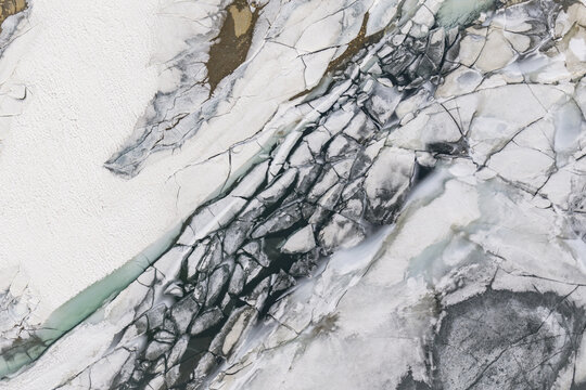 Aerial view of Valchiavenna glacier with deep crevasses, textured ice formations, and snow-covered terrain Lombardia, Italy.