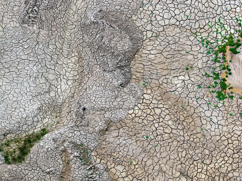Aerial view of the cracked, dry earth at the Tagebau Hambach open-pit mine with patches of sparse green vegetation in Elsdorf, Nordrhein-Westfalen, Germany.