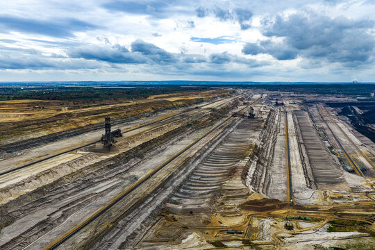 Aerial view of the Tagebau Hambach open-pit coal mine with massive excavators, terraced earth, and industrial infrastructure under a cloudy sky in Elsdorf, Nordrhein-Westfalen, Germany.