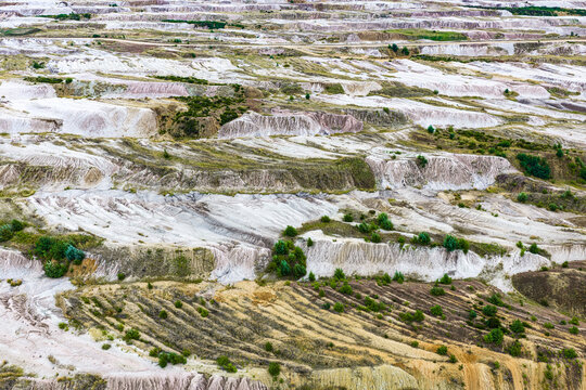 Aerial view of the terraced landscape at Tagebau Hambach featuring exposed soil layers, erosion patterns, and sparse vegetation in Elsdorf, Nordrhein-Westfalen, Germany.