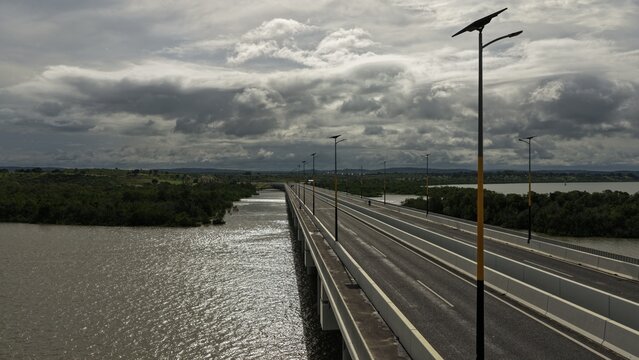 Aerial view of Dongo Kundu Bypass bridge spanning over water with lush mangroves, modern street lighting, and a cloudy sky in Mombasa, Wilaya ya Mombasa, Kenya.
