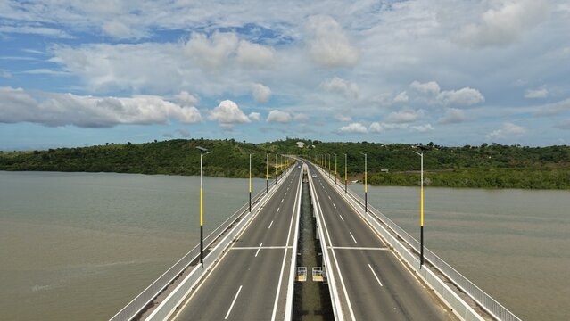Aerial view of the Dongo Kundu Bypass bridge spanning across the water with lush green hills in the background under a cloudy sky in Mombasa, Wilaya ya Mombasa, Kenya.