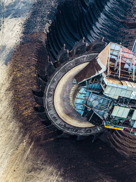 Aerial view of the massive bucket-wheel excavator operating at the Garzweiler surface mine, showing the deep brown earth and industrial machinery in Juchen, North Rhine-Westphalia, Germany.