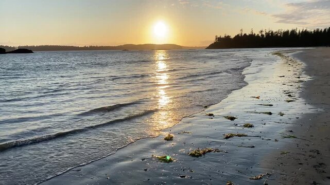 Sunset over a calm beach with waves gently touching the shore, Long Beach, Tofino, British Columbia, Canada