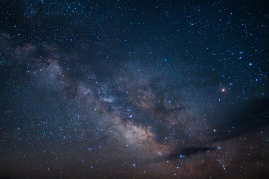 View of the Milky Way galaxy stretching across the night sky above the desert landscape in Moab, Utah, United States.