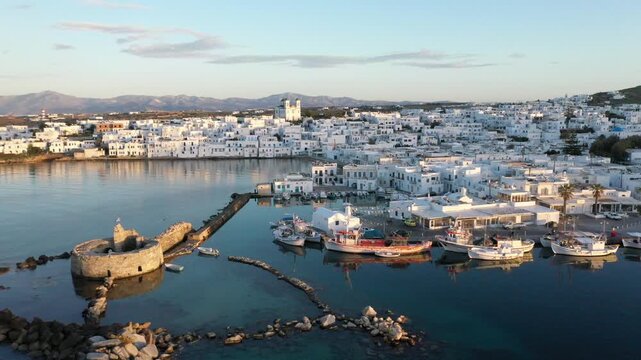 Coastal seaside town at sunset with white buildings and boats, Naousa, Paros, Greece