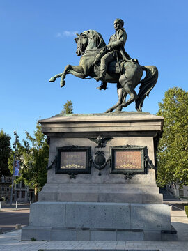 Equestrian statue of Napoleon Bonaparte on a stone pedestal, with a bicycle and pedestrians nearby beneath a blue sky - Rouen, France - September 5, 2026