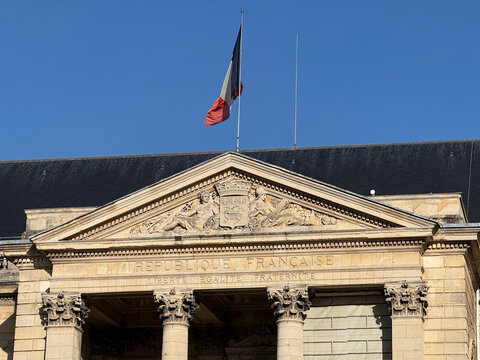 A French flag flies above the stone portico of Rouen city hall, featuring carved figures, ornate columns and French republican inscriptions - Rouen, France - September 5, 2026