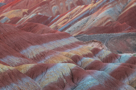 View of the colorful striped rock formations of the Zhangye Danxia National Geopark with vibrant red, orange, and yellow mineral layers in Zhangye, Gansu, China.