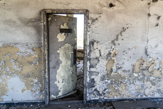 View of a weathered, peeling door set within a decaying, textured wall inside an abandoned building in Devnya, Varna, Bulgaria.