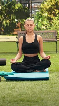 Vertical aspect: Group of people meditating cross-legged on yoga mats with closed eyes