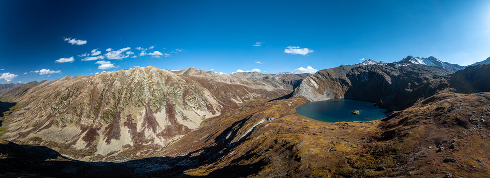 Aerial view of Maheen Lake nestled among rugged mountain peaks with rocky slopes and clear blue sky in Batakundi, Khyber Pakhtunkhwa, Pakistan.