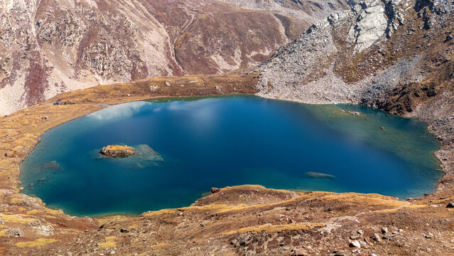Aerial view of Maheen lake surrounded by rugged mountain slopes and rocky terrain in Batakundi, Khyber Pakhtunkhwa, Pakistan.