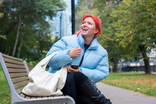 Mid adult 44 years old woman laughing on wooden bench in autumn park