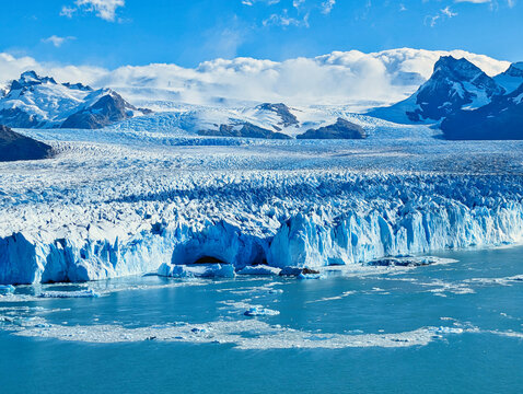 View of Perito Moreno Glacier with massive ice walls, blue crevasses, and floating icebergs in the glacial lake. Lago Argentino Department, Santa Cruz Province, Argentina.