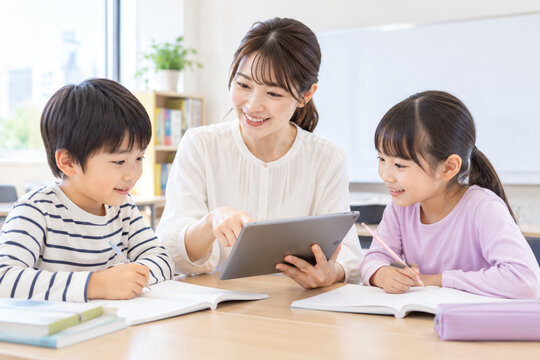 塾でタブレット学習する小学生と女性講師