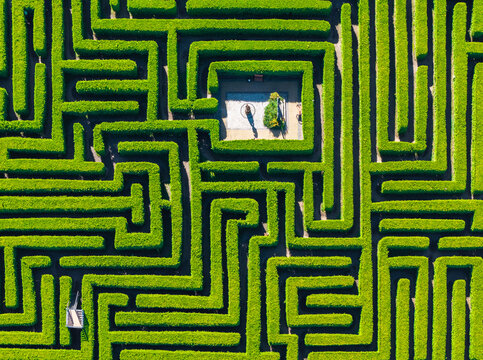 Aerial view of a green hedge maze with a central stone courtyard and pathways in Leba, Pomeranian Voivodeship, Poland.