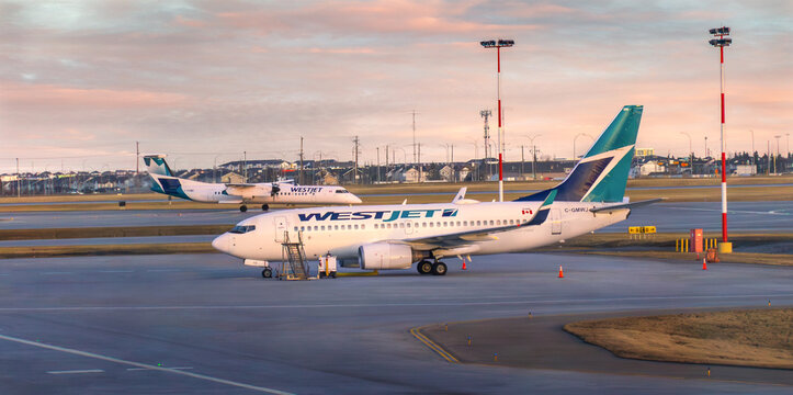 Calgary, Alberta, Canada - 02 13 2025: WestJet commercial passenger jet parked on tarmac at Calgary International Airport YYC at sunset with second aircraft in background