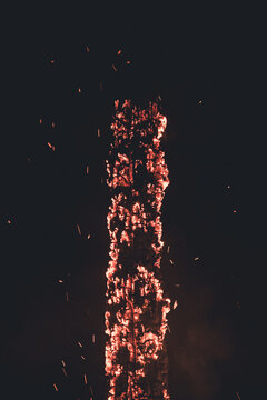 View of a tall wooden pole burning with bright glowing embers and sparks against a dark night sky in Laane County, Estonia.