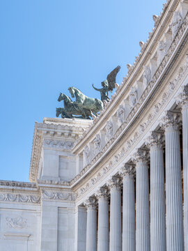 View of the bronze quadriga sculpture atop the Altare della Patria, featuring neoclassical columns and clear blue sky in Rome, Lazio, Italy.