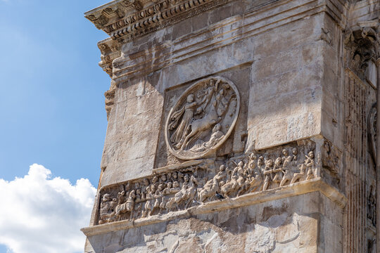 View of the intricate ancient marble bas-reliefs and sculptures on the Arch of Constantine, showcasing detailed Roman carvings against a clear blue sky in Rome, Lazio, Italy.