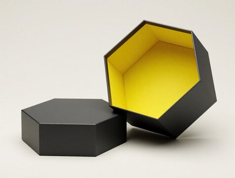 Minimalist black hexagonal gift box with bright yellow interior. One open empty container shows glowing yellow lining. Second lid sits beside on plain background. Modern geometric packaging for