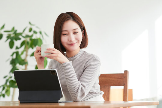 リビングでタブレットPCを見る女性