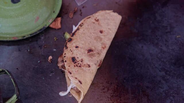 Mexican street food taco cooking on a hot comal