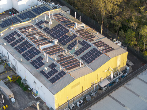 Melbourne, VIC, Australia - 05 October 2026: Aerial view of an industrial factory building featuring extensive rooftop solar panel installations and ventilation units.