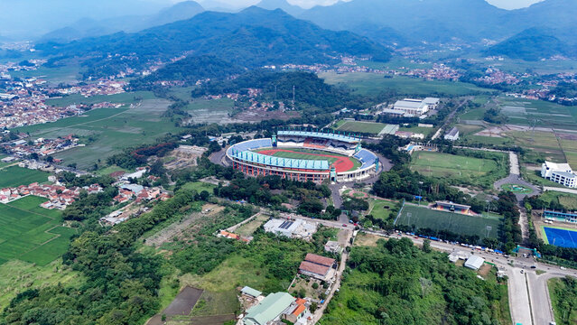 Bandung, Indonesia - 12 May 2025: Aerial view of Si Jalak Harupat Stadium surrounded by lush green fields and mountains in West Java.