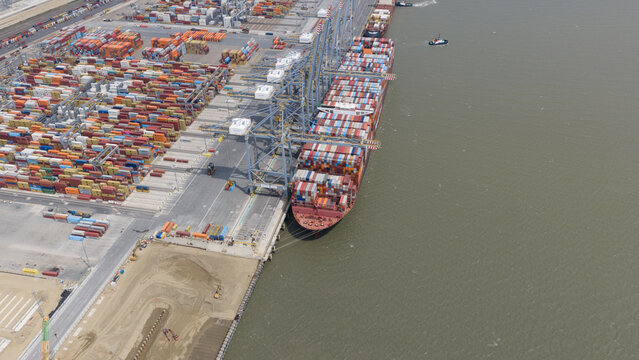 Corringham, United Kingdom - 10 July 2026: Aerial view of DP World London Gateway Port with a large container ship docked at the quay and stacked shipping containers.