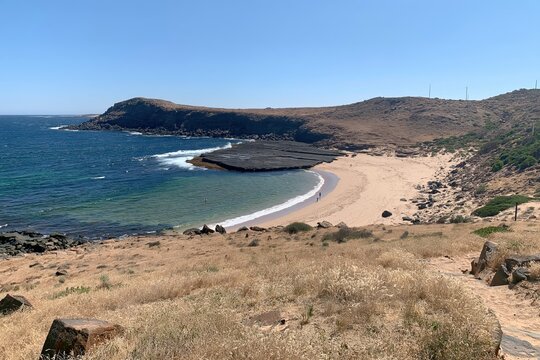 Coastal beach with rocky headland and dry hills