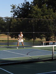 Woman hitting tennis ball near net on sunny day, USA © Maria Rasin